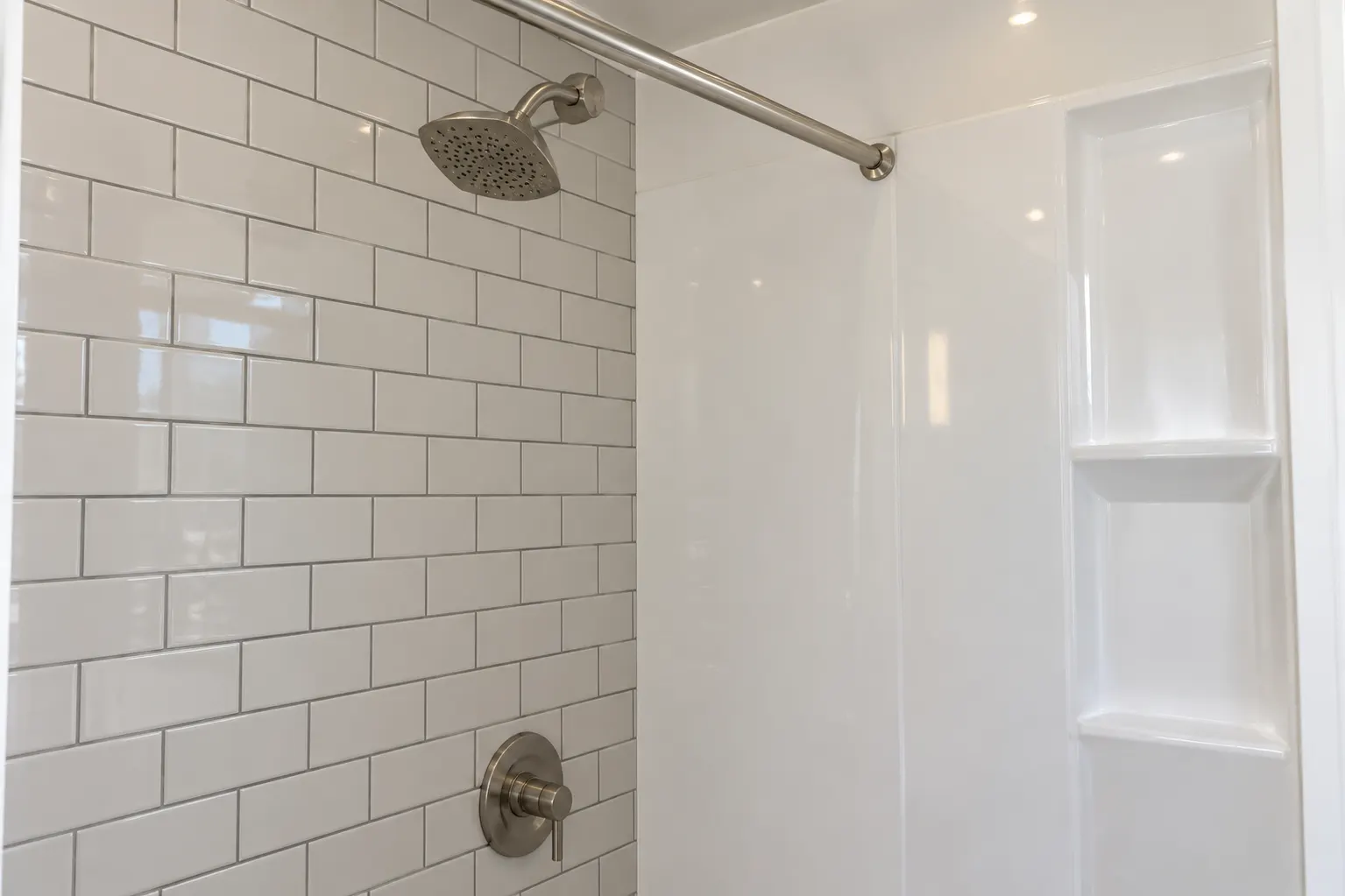 Tiled shower wall next to an acrylic shower panel